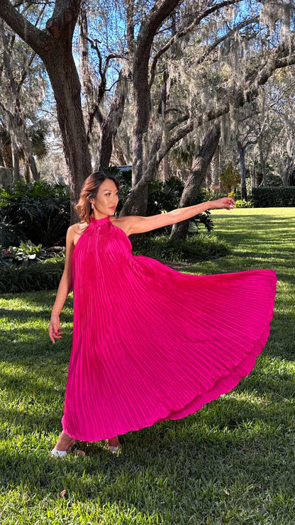 ShopJenny Boutique model is pictured wearing Charlotte Satin Pleated Halter Midi Dress - Fuchsia made by Strut & Bolt.