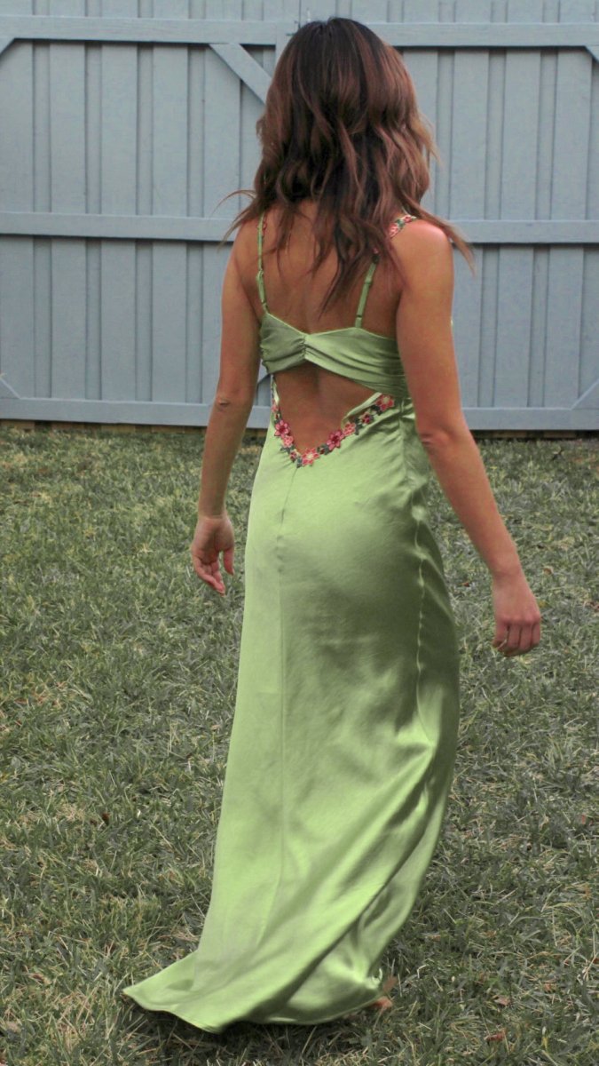 ShopJenny Boutique model is pictured wearing Zoey Satin Floral Maxi Dress - Matcha Green made by Saints & Secrets.