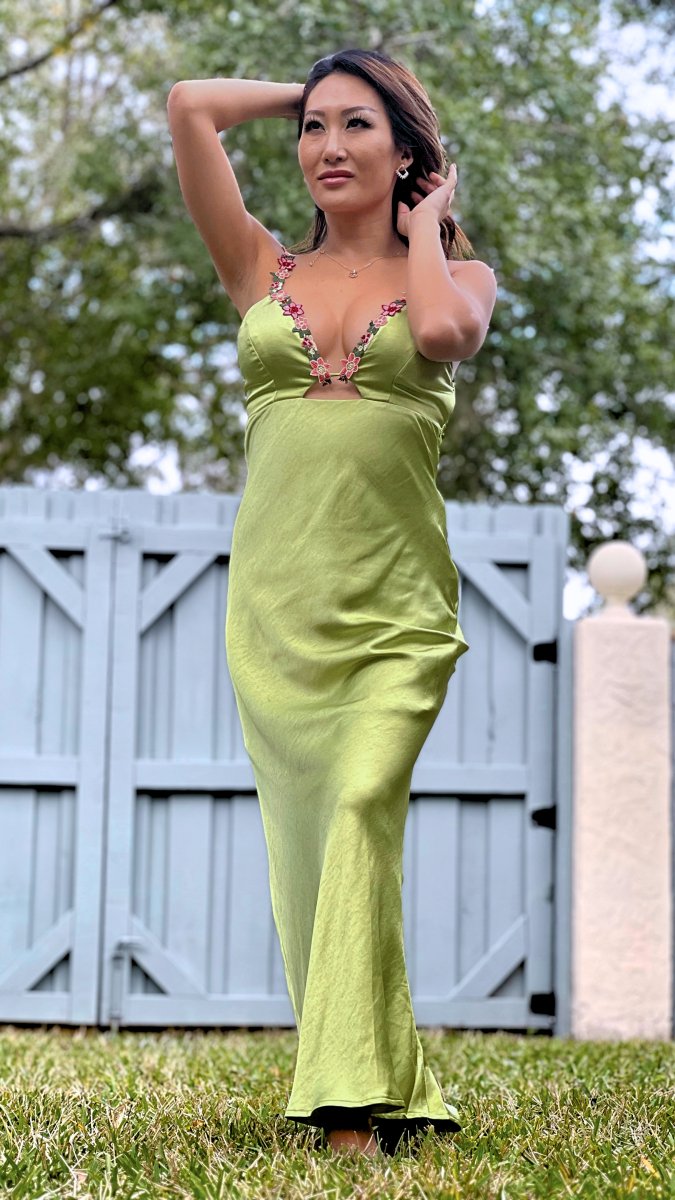 ShopJenny Boutique model is pictured wearing Zoey Satin Floral Maxi Dress - Matcha Green made by Saints & Secrets.